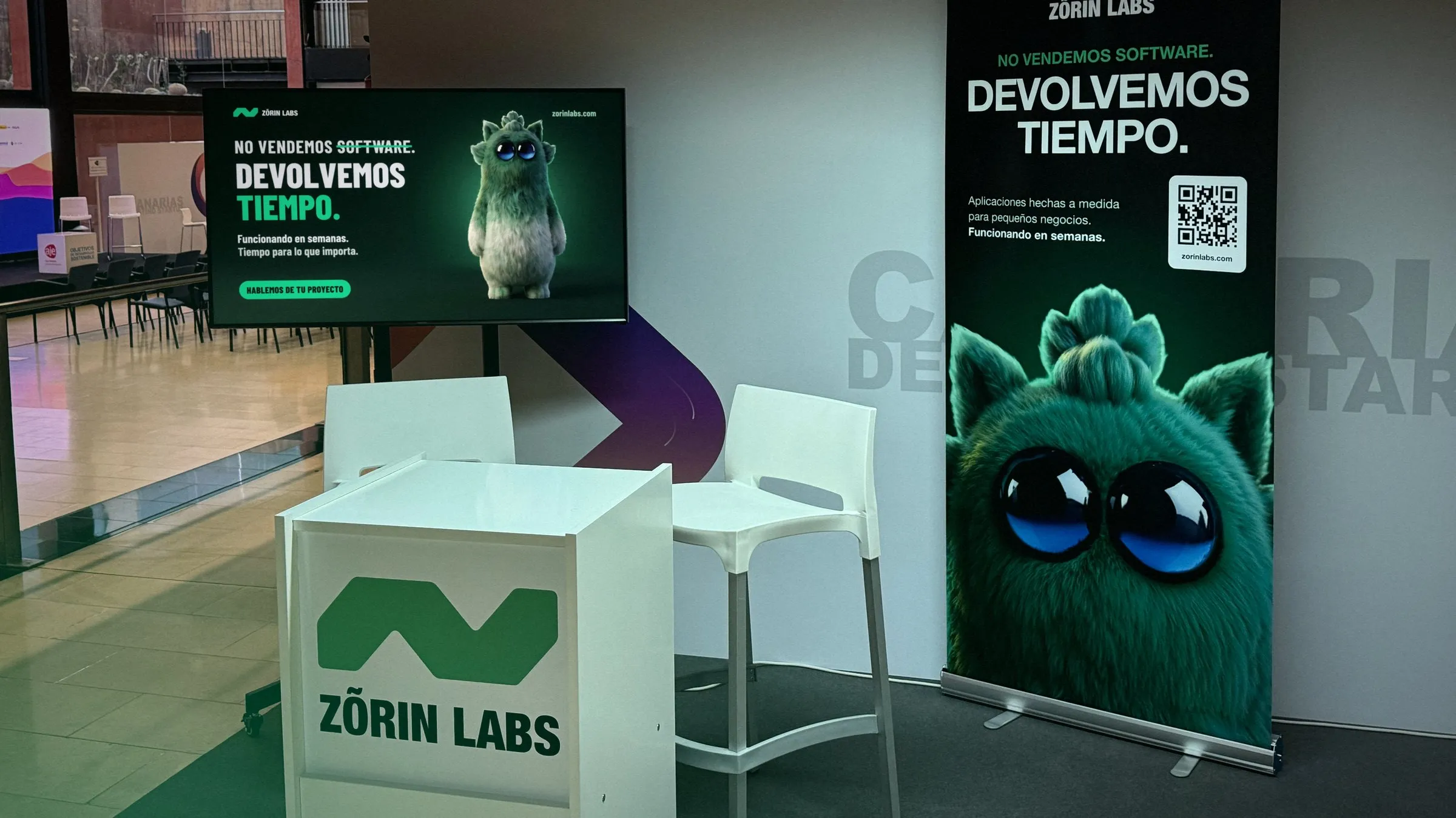 El stand de Zõrin Labs en Canarias Destino Startup, con la mesa, la pantalla y el roll-up de la mascota.